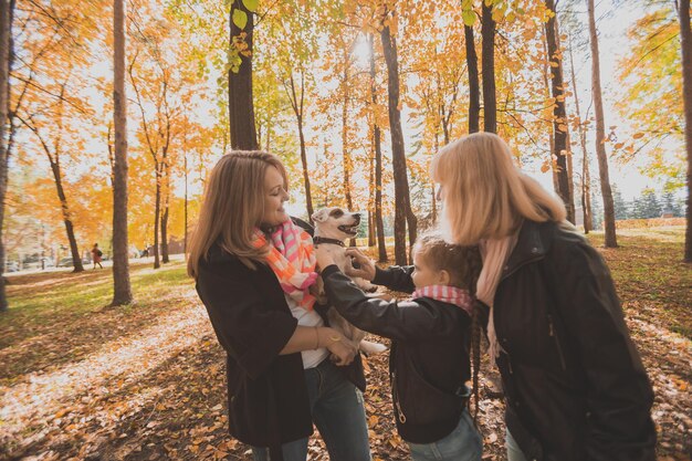 Madre, nonna e figlia tengono jack russell terrier e ci giocano in autunno fuori