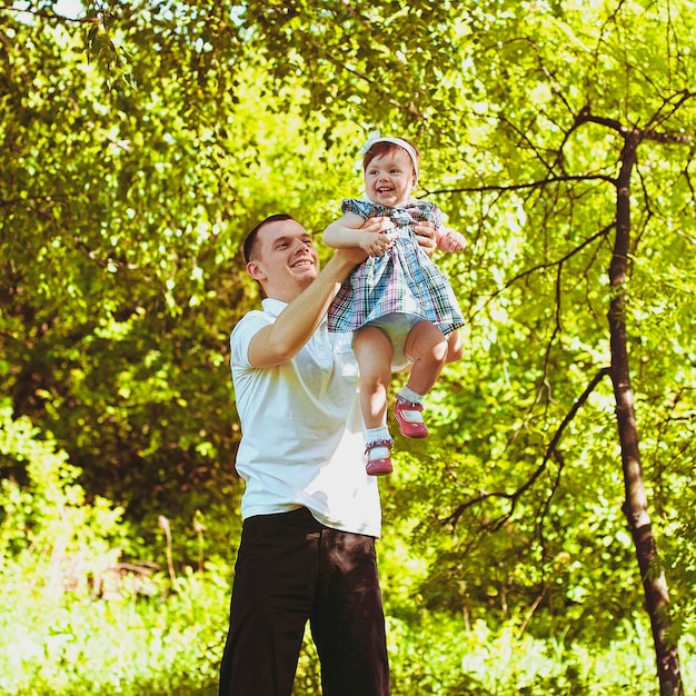 Madre, padre, bambina che cammina in città, parco verde. ridendo in una giornata di sole. Divertirsi. Famiglia