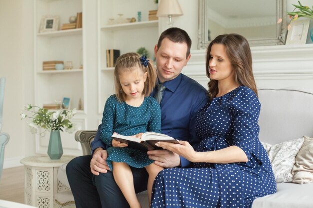 Madre padre e figlia del bambino che leggono insieme un libro a casa