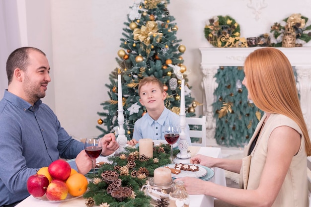 Madre, padre e figlio, sono seduti a un tavolo festivo alla vigilia di Natale