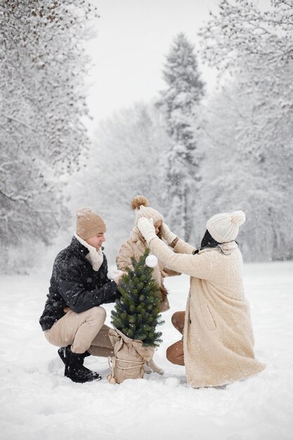 Madre padre e la loro piccola figlia che giocano all'aperto durante il giorno d'inverno