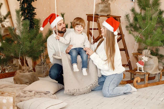 Madre padre vicino al figlio seduto su un'altalena alla vigilia di Natale