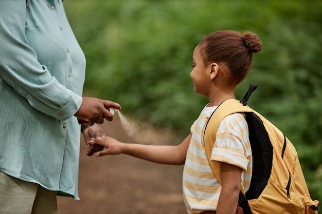 Madre premurosa che usa un repellente per insetti sicuro per il bambino per la figlia durante il viaggio