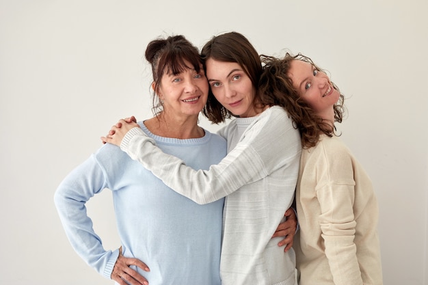 Madre sorridente che abbraccia le figlie e guarda la telecamera