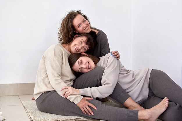 Madre sorridente che abbraccia le figlie e guarda la telecamera