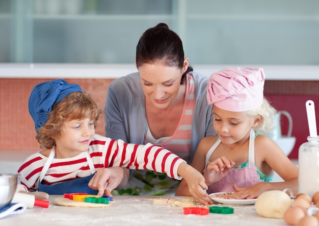 Madre sorridente che cuoce con i suoi bambini