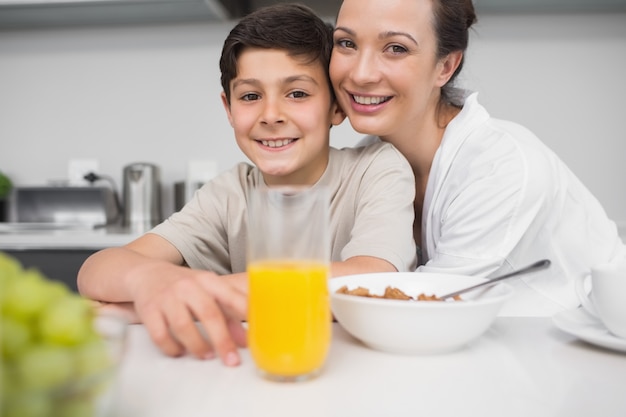 Madre sorridente con il figlio al tavolo della colazione in cucina