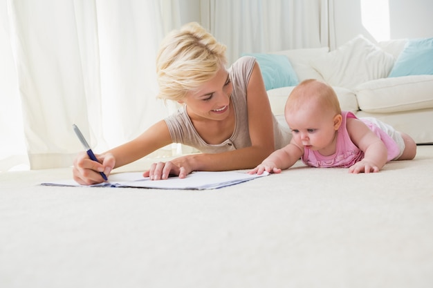 Madre sorridente con la sua neonata che scrive su un quaderno