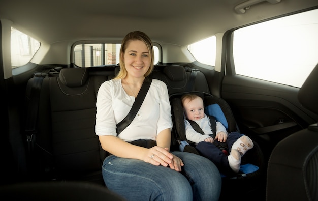 Madre sorridente felice con il suo bambino sul sedile posteriore