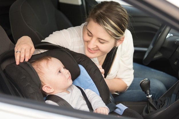 Madre sorridente in macchina con il suo bambino nel seggiolino di sicurezza