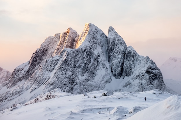 Maestosa montagna innevata con alpinista sulla collina di neve al sorgere del sole