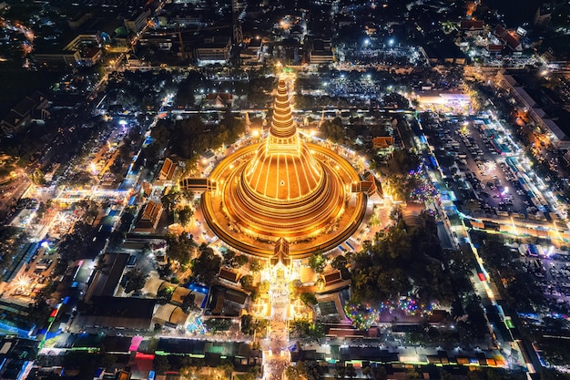Maestosa pagoda dorata di Phra Pathom Chedi che risplende tra le luci del festival intorno alla rotatoria nel centro di Nakhon Pathom