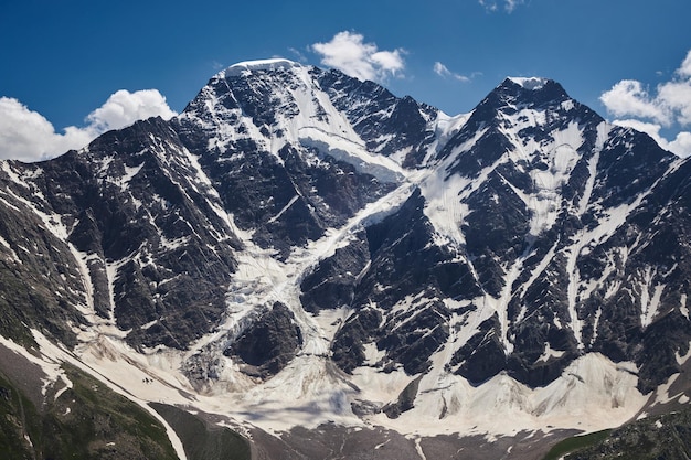 Maestose montagne coperte di neve con profondi creppi e ghiacciai contro un cielo blu con nuvole sottili