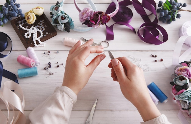 Maestro che realizza gioielli fatti a mano, donna pov. Posto di lavoro di ricamatrice con perline di plastica, fiori e strumenti per creare accessori