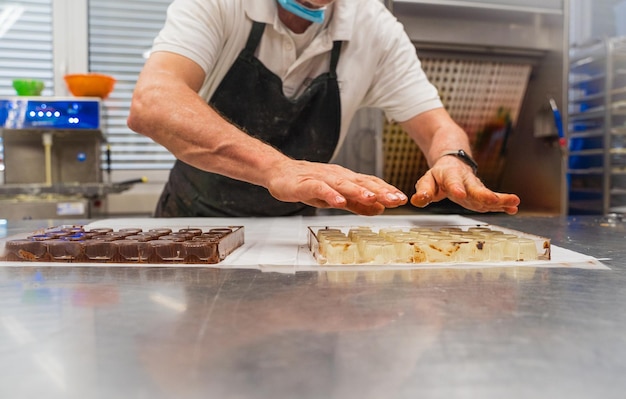 Maestro cioccolatiere che lavora con il cioccolato nella cucina del suo negozio