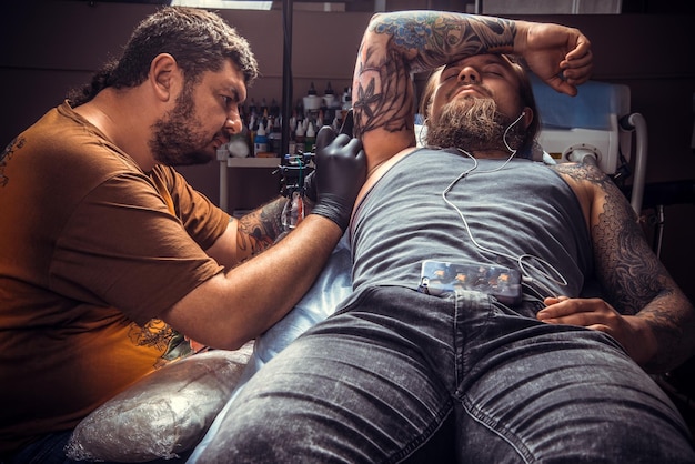 Maestro del tatuaggio che fa un tatuaggio in un negozio di tatuaggi./Tatuatore professionista che fa un tatuaggio in uno studio di tatuaggi.