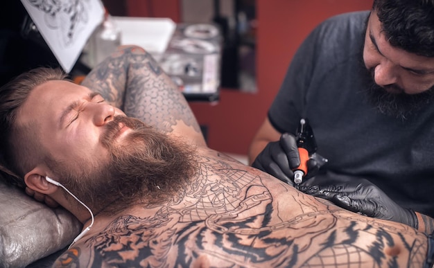 Maestro del tatuaggio che lavora su un dispositivo professionale per macchinette per tatuaggi nel salone di tatuaggi