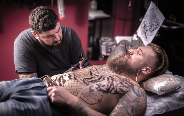 Maestro dell'arte del tatuaggio che mostra il processo di realizzazione di un tatuaggio in studio di tatuaggi.