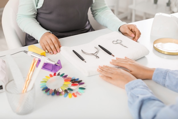 Maestro di manicure che lavora con una cliente femminile nel salone di bellezza