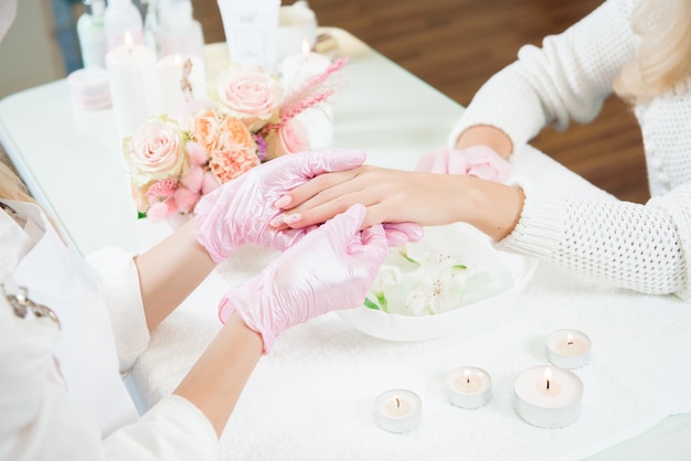 Maestro di manicure che tiene le mani femminili in un salone di bellezza.