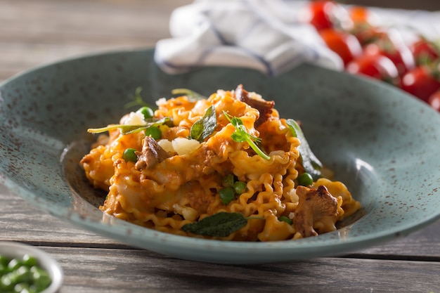 Mafalde di pasta italiana funghi piselli e salsa di pomodoro.