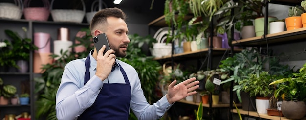 Magazziniere di fiori in un garden center che risponde a una telefonata