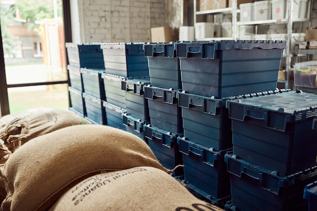 Magazzino del caffè con sacchi di tela e scatole di plastica blu con coperchi