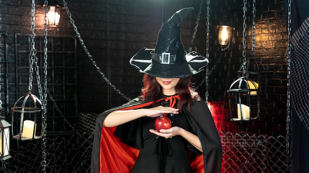 Magia su Halloween Bella donna vestita da strega per Halloween utilizzando la magia con la mela in tema di Halloween