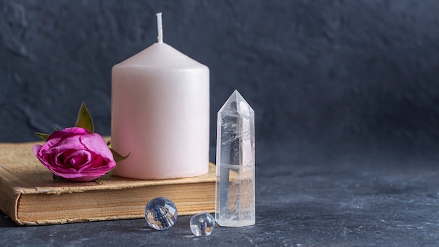 Magica natura morta vintage con cristalli rosa candela vecchio libro e fiori di rosa
