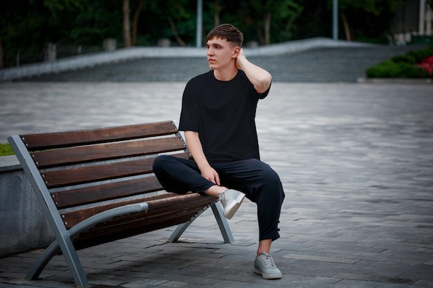 Maglietta casual nera su un ragazzo seduto su uno sfondo sfocato