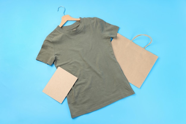 Maglietta vuota, borsa e foglio di cartone su sfondo blu