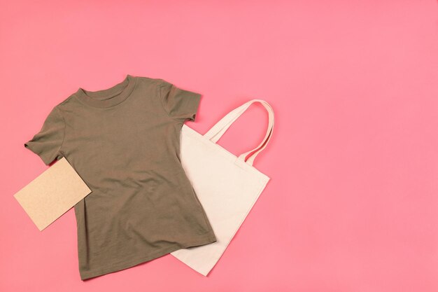 Maglietta vuota, borsa e foglio di cartone su sfondo rosa