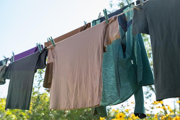 Magliette maschili di colori scuri appese alla corda in giardino Bella giornata di sole in campagna per asciugare i vestiti all'aperto