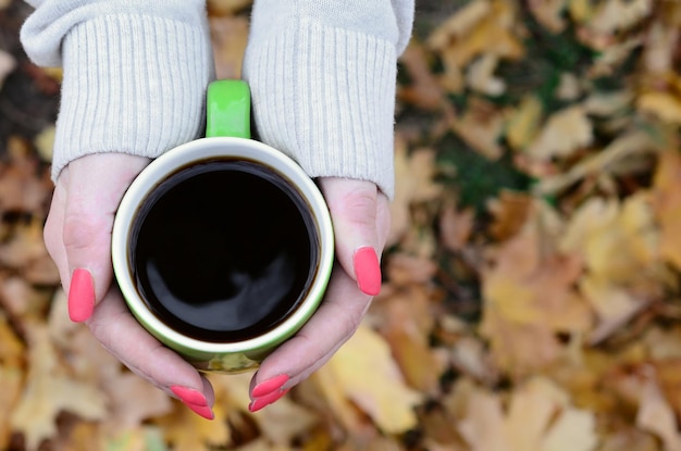 Maglione bianco da portare della donna che tiene una tazza di caffè verde