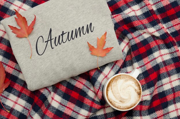 Maglione grigio, plaid e tazza da caffè. Foglie d'autunno. Concetto alla moda