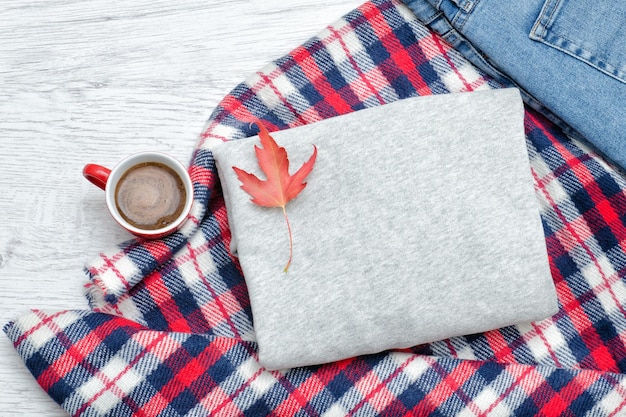 Maglione grigio plaid jeans tazza da caffè e foglie autunnali Concetto alla moda