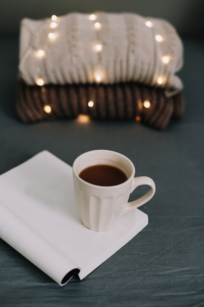 Maglione lavorato a maglia, caldo plaid, un libro e una tazza di caffè