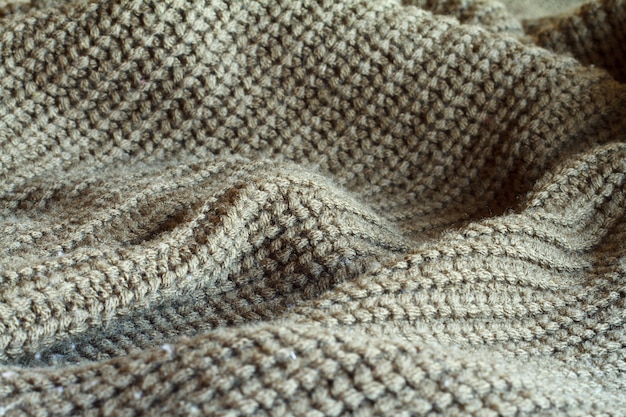 Maglione lavorato a maglia color oliva in primo piano realizzato con trama di lana naturale, pieghe ondulate