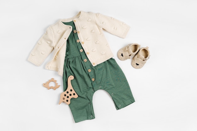 Maglione lavorato a maglia con pagliaccetto verde, giocattoli in legno e scarpe per bambini. Set di vestiti e accessori per bambini