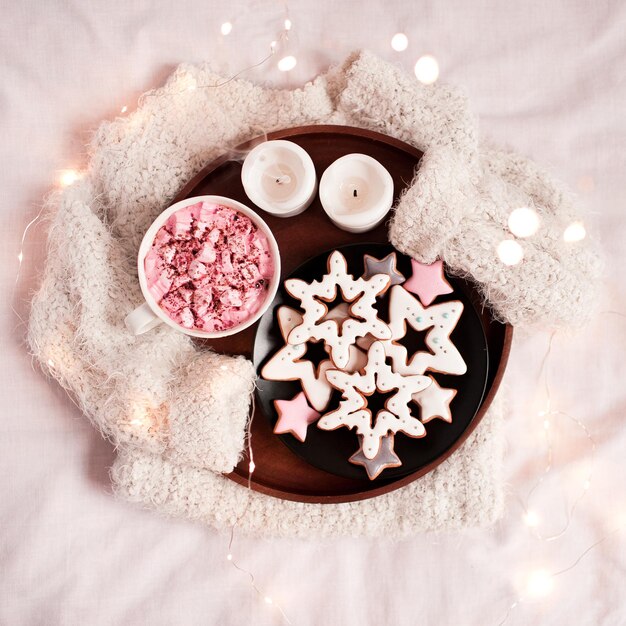 Maglione lavorato a maglia con vassoio in legno e panpepato, candele, tazza di caffè con primo piano marshmallow. Buon giorno. Stagione delle vacanze invernali. Natale.