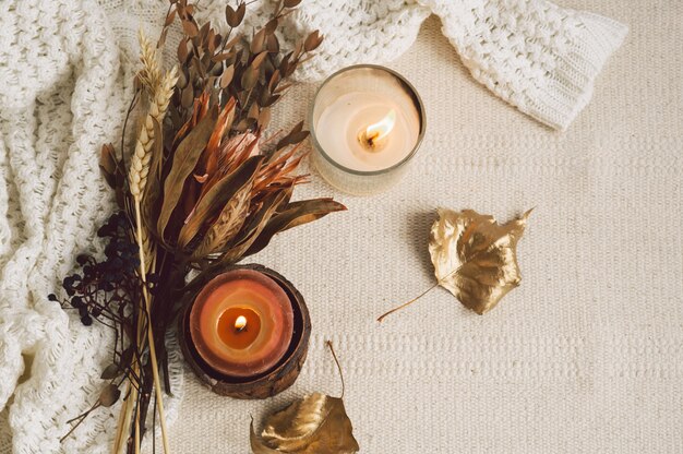 Maglioni caldi, candele e bouquet di fiori secchi