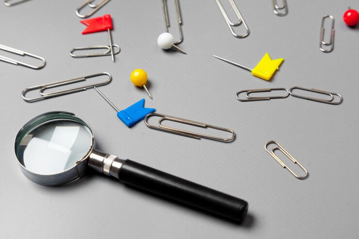 Photo magnifying glass with paper clips on grey