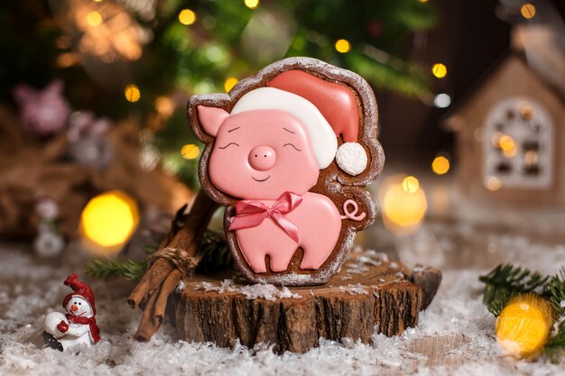 Maiale rosa di Pan di zenzero felice in cappello di natale in accogliente decorazione calda con luci ghirlanda