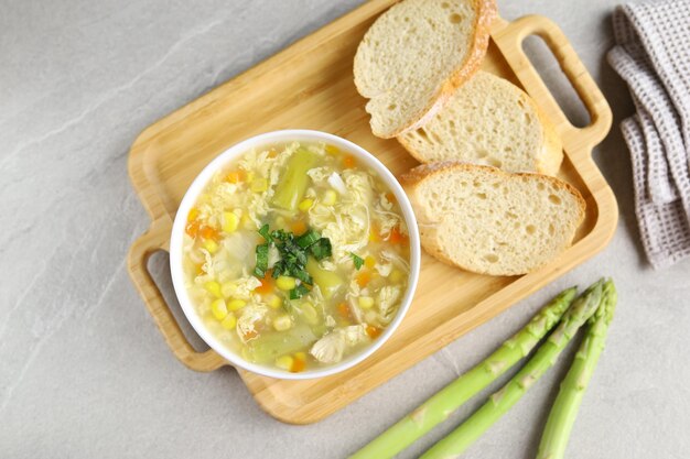 Mais e asparagi con zuppa di gocce d'uovo in una ciotola bianca e pane croccante