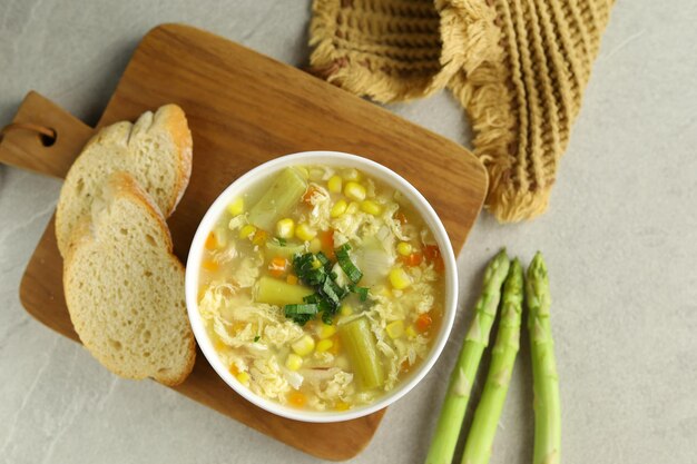 Mais e asparagi con zuppa di gocce d'uovo in una ciotola bianca e pane croccante