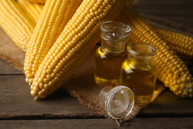 Mais fresco con bottiglie di olio sul tavolo da vicino