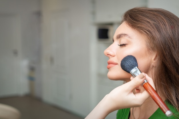 Make up artist che applica un trucco professionale di fondotinta tonale