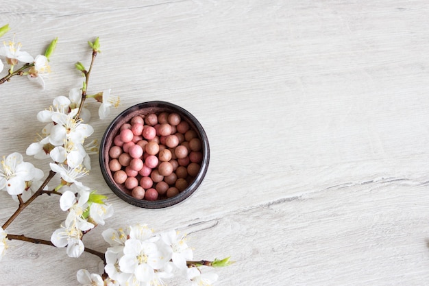 Make up Balls fard cosmetici naturali per la cura della pelle. Rametto di ciliegio in fiore su un tavolo di legno. Cosmetologia e concetto di spa