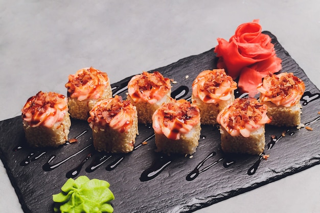 Maki Sushi Rolls con salmone su pietra nera su sfondo scuro. Con zenzero e wasabi. Menu di sushi. Cibo giapponese. Primo piano di delizioso cibo giapponese con rotolo di sushi. Foto orizzontale.