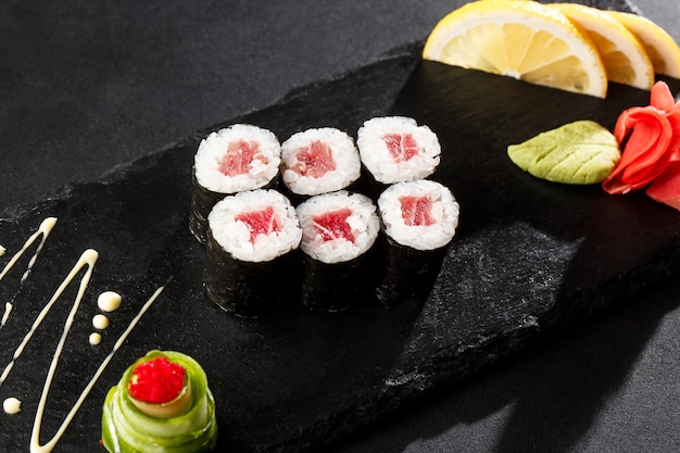 Maki Sushi Rolls con tonno su pietra nera su oscurità